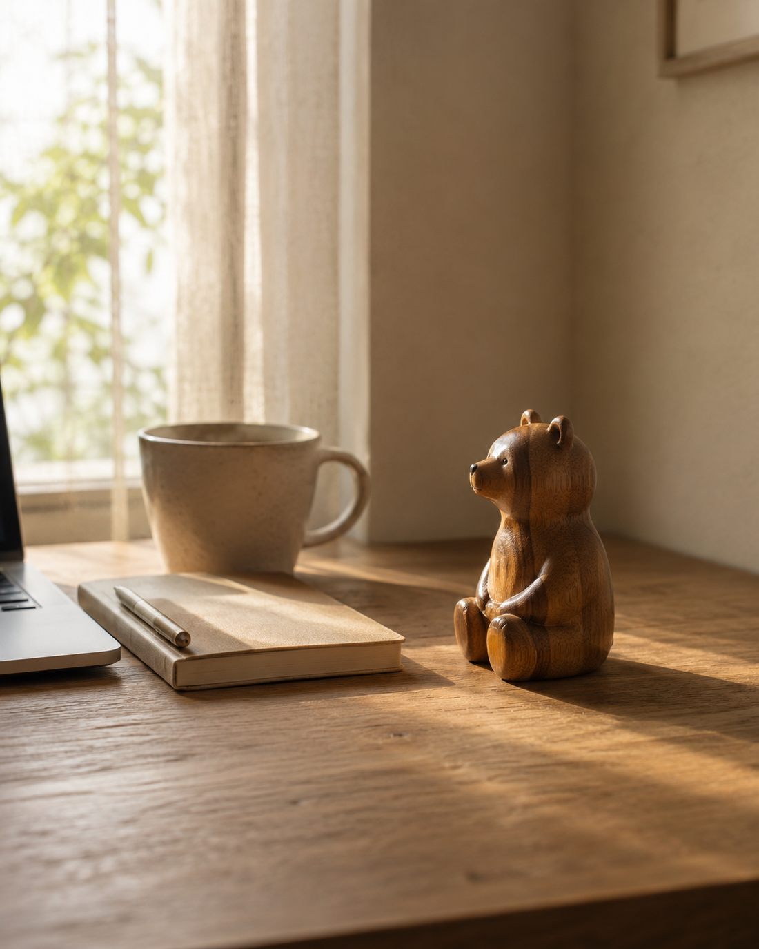 Small handcrafted wooden bear on a desk near a window in morning light