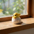 Decorative bird figurine on a windowsill with natural light