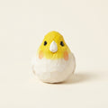 Small ceramic bird figurine with a yellow head and white body on a beige background