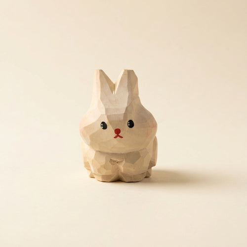 Wooden rabbit figurine on a beige background